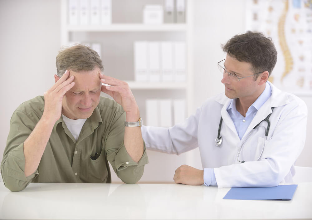 Doctor comforting mature stressed patient with headache